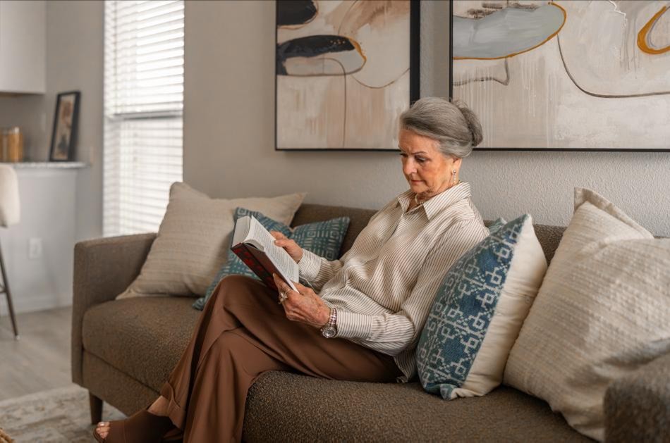 Photo of a woman reading in her Origin floor plan, a small home by Betenbough Homes.