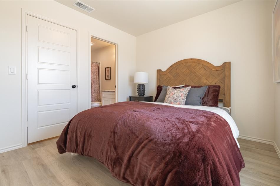 Photo of a staged bedroom and bathroom in a Betenbough Homes' Origin floor plan.