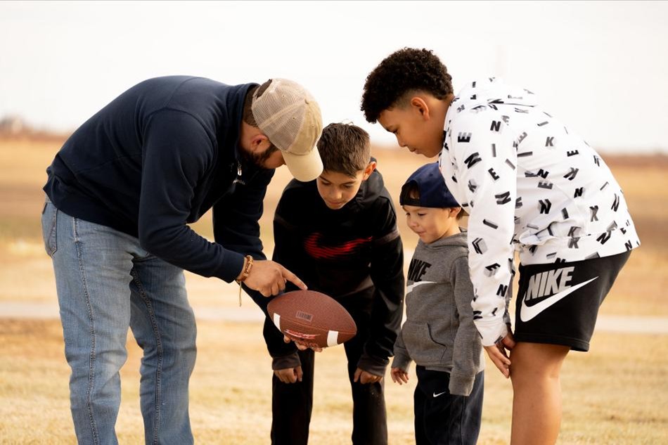 A dad calls a football play to a group of boys in his Betenbough Homes community.