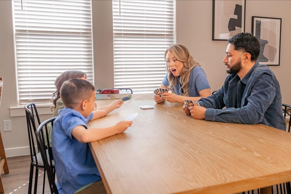 Family Game Comp Photo of a family playing a card game at the dining room table in their Betenbough home.