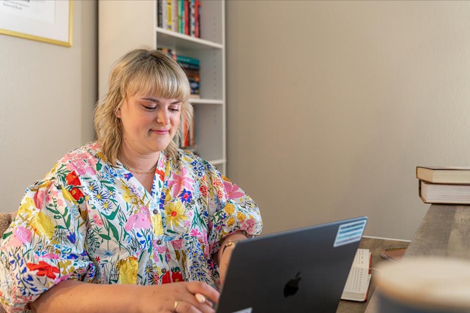Photo of a homeowner on her laptop in her Betenbough home.