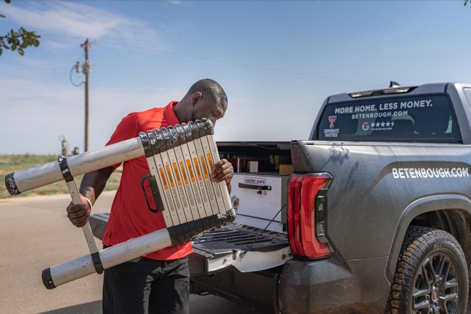 A member of the Betenbough Homes warranty team loads a ladder into his truck after performing warranty work on a new home.