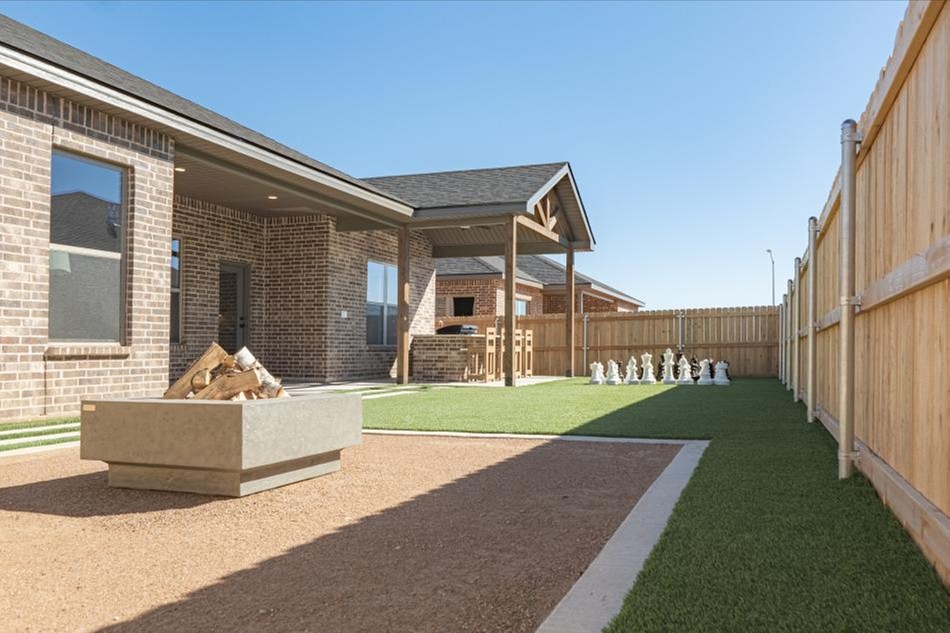 Photo of the backyard of the Betenbough Homes Odessa 2025 parade home, complete with outdoor kitchen, life-size chess set, and fire pit.