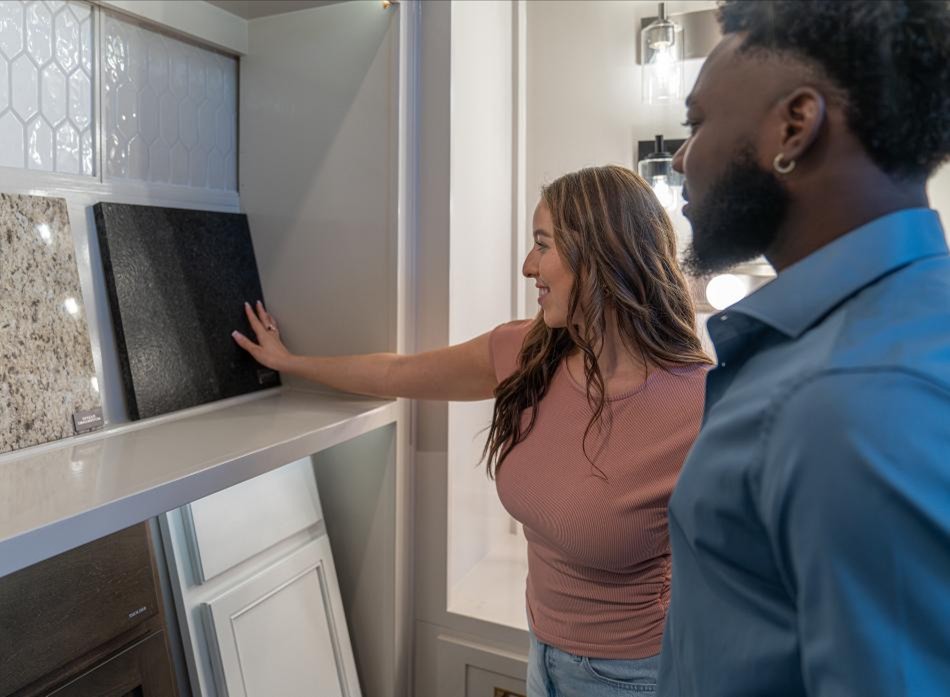 A couple is in a Betenbough Homes design studio choosing their granite, cabinets, and other new home options.