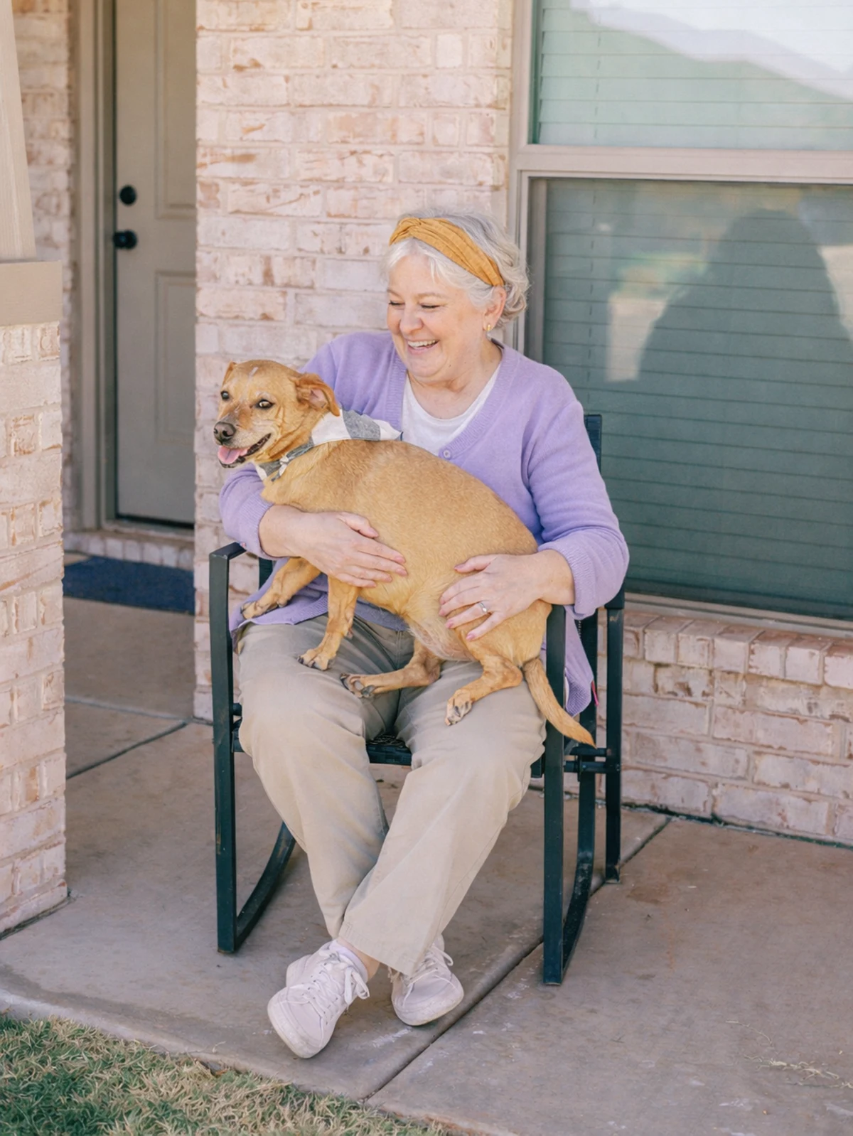 Elderly woman holding her dog sitting in a rocking chair on the porch of her Betenbough origin home