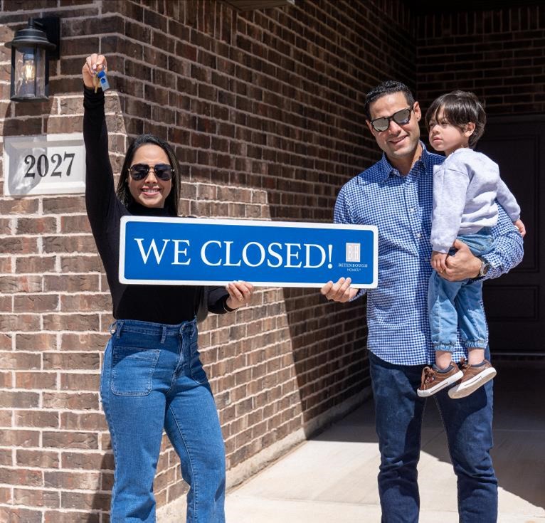 Photo of a young family holding the keys to their new Betenbough home and a