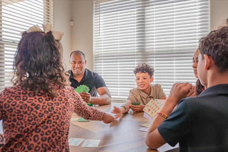Photo of a family playing a game at the dining table in their Betenbough home.