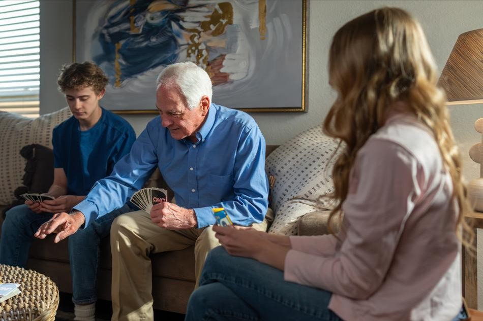 Photo of a man playing Uno with his grandchildren in his Origins home by Betenbough Homes.